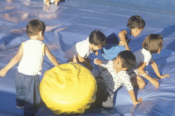 Five children play with a yellow ball.