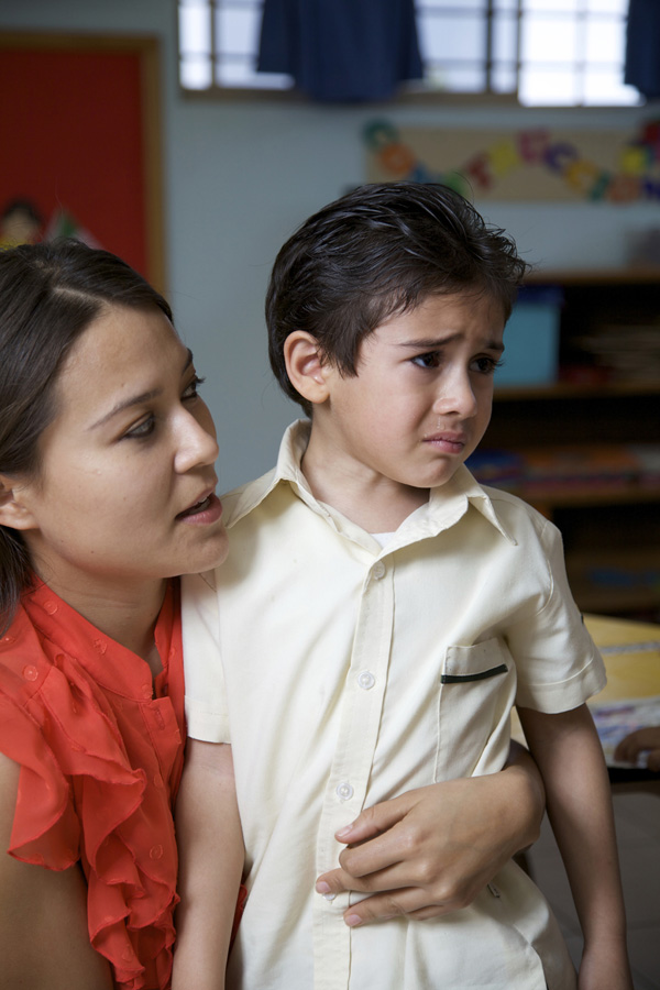 Teacher talking to small boy who is obviously upset.